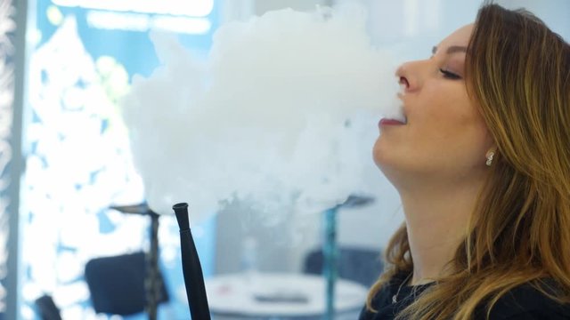 Young, beautiful woman in the night club or bar smoke a hookah or shisha. The pleasure of smoking. Sexy smoke.