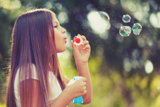 Young female child blowing soap bubbles