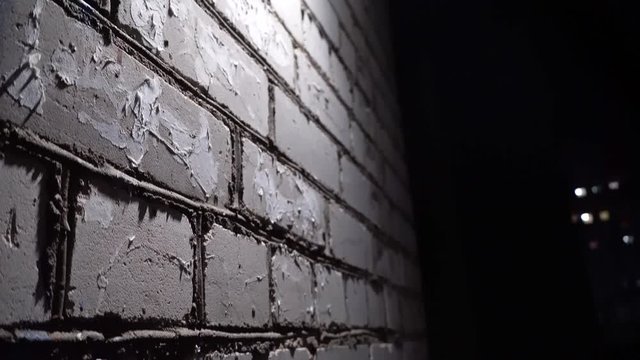 a wall of white brick, at night, illuminated by a lantern, danger, fear, horror.