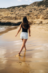 Back young woman walking on the beach during summer holiday