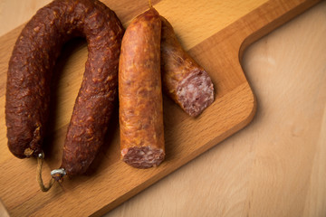 Luftgetrockneter Mettwurst Ring und frische Bierbeißer, zwei Salami Sorten aus Schweinefleisch auf Holz Brett 