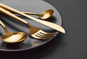 Gold cutlery set on black background