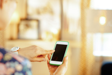 Closeup on modern housewife with smartphone in the house.