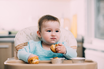 the little girl in the highchair in the hands Krapina, like muffins and croissants trend 2019