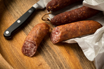 Ringwurst Salami und Bierbeißer Wurst in Wachspapier mit Messer auf Vesper Holzbrett