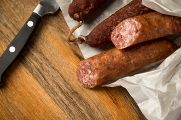 Ringwurst Salami und Bierbeißer Wurst in Wachspapier mit Messer auf Vesper Holzbrett