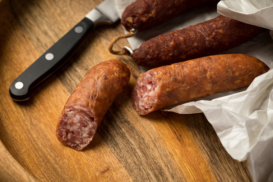 Ringwurst Salami und Bierbei&szlig;er Wurst in Wachspapier mit Messer auf Vesper Holzbrett