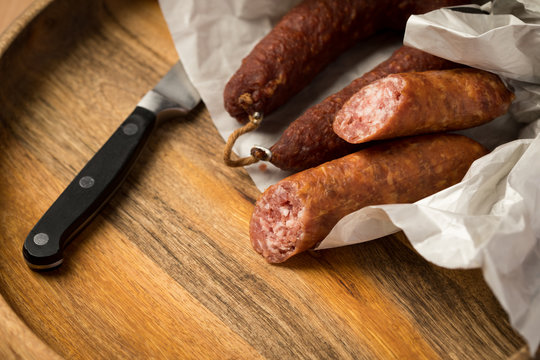 Ringwurst Salami und Bierbei&szlig;er Wurst in Wachspapier mit Messer auf Vesper Holzbrett