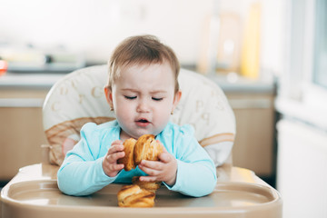 the little girl in the highchair in the hands Krapina, like muffins and croissants trend 2019