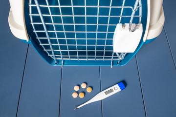Cage carrying in the veterinary clinic with meds and a thermometer, flat lay view. The concept of disease and health care for Pets