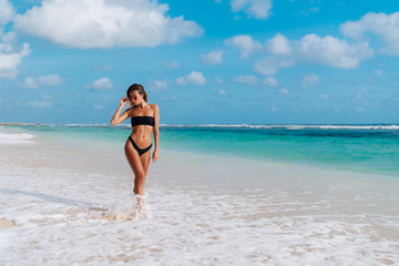 Girl with sexy body in swimwear sunbathes on white sand beach
