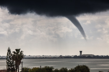A rope tornado above the runway and airport traffic control tower. Danger for traffic air...