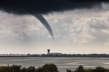 A rope tornado above the runway and airport traffic control tower. Danger for traffic air...