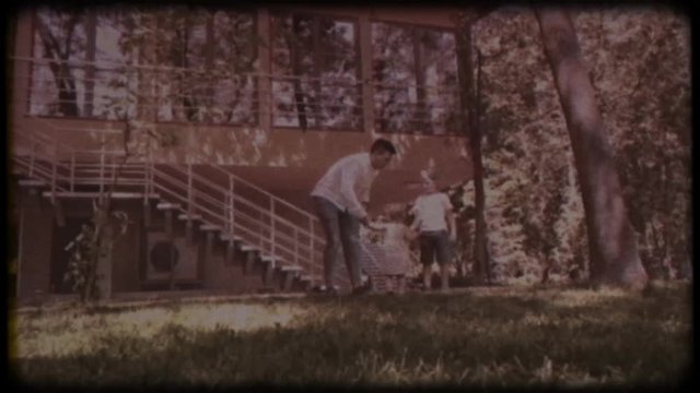 Family video archive. Retro camera 8 mm. Old film. Young father playing with his little daughter and son near the house. Family games. Holiday, holidays. Family together