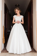 Fototapeta premium Fashion bride in gorgeous wedding dress studio portrait. Beautiful model with bridal makeup and hairstyle in marriage lace dress.