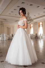 Fototapeta premium Beauty portrait of bride wearing fashion wedding dress with feathers with luxury delight make-up and hairstyle, studio indoor photo