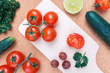 Raw Vegetable Ingredients on Kitchen Table. Top View Tomatoes and Cucumbers with Lime and Grape.