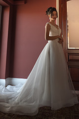 Portrait of a beautiful bride woman in elegant white wedding dress. Luxurious apartments. 