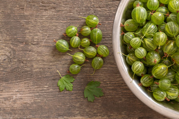 Ripe gooseberry on a rustic wood in the bowl place for text, top view, summer harvest of berries