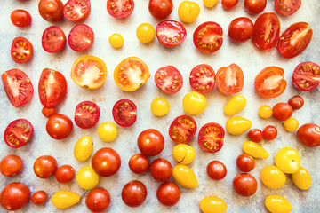 Red, Yellow and Orange Whole and Cut Cherry Tomatoes on Paper Background