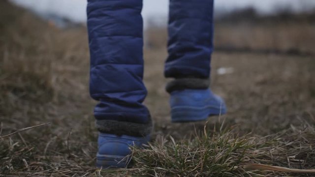 The woman in galoshes comes out on the ashes in the broken ground near the river.
