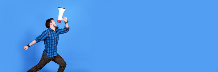 bearded hipster shouting into a megaphone on a blue background, panoramic image with place for text