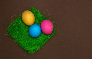 Colorful Easter eggs on grass and chocolate background. Three eggs