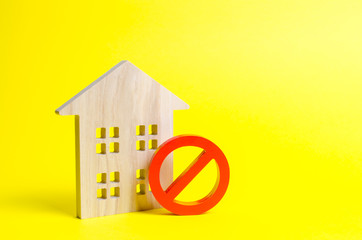 Wooden house figurine and a red symbol NO or ban. The concept of inaccessibility or lack of housing. There is no opportunity to buy a house or pay for rent. The house can not be put into operation.