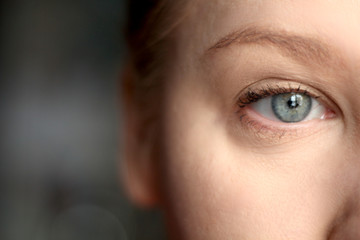 Female Slavic young gray-blue eye with mascara  and light brown eyebrows close-up photo of half face without makeup natural beauty with clean skin