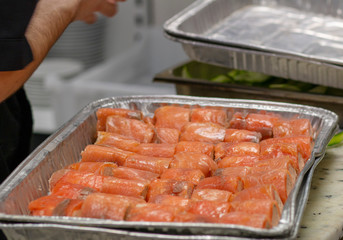 rolls of red fish lie in a tray