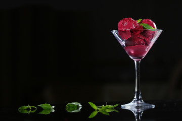 Beetroot ice cream in a tall martini glass on a black background. Still life concept.
