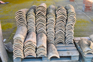 Piles of old roof tiles in many rows with different number in any column. The ancient tiles are...