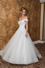Fototapeta premium Beauty portrait of bride wearing fashion wedding dress with feathers with luxury delight make-up and hairstyle studio indoor photo.