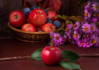 Composition of beautiful red apples, plums, flowers