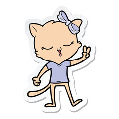 sticker of a cartoon cat with bow on head giving peace sign