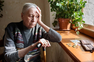 Portrait of an old woman counting money, euros. The concept of old age, poverty, austerity.