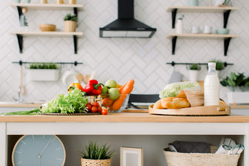 Fresh healthy food, milk and bread on the wooden table and blurred view of kitchen interior on background