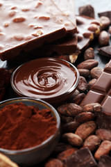 Melting chocolate or melted chocolate with a chocolate swirl and stack, chips and powder on black