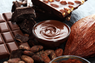 Melting chocolate or melted chocolate with a chocolate swirl and stack, chips and powder on black