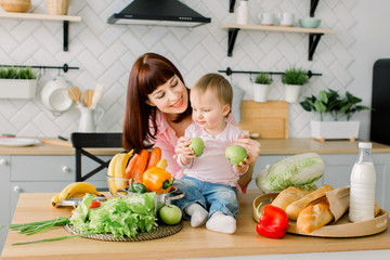 Mother with her daughter in the kitchen preparing healthy food with fresh vegetables, home parenting life style