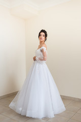 Naklejka premium Beautiful bride wearing fashion wedding dress with feathers with luxury delight make-up and hairstyle studio indoor photo shoot