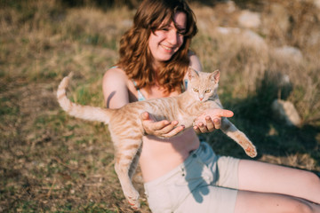 Girl playing with a cat outdoors.