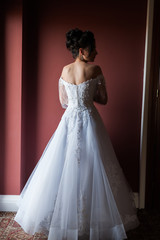 Fototapeta premium Beautiful bride wearing fashion wedding dress with feathers with luxury delight make-up and hairstyle studio indoor photo shoot