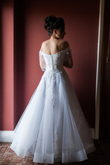 Fototapeta premium Beautiful bride wearing fashion wedding dress with feathers with luxury delight make-up and hairstyle studio indoor photo shoot