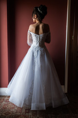 Fototapeta premium Beautiful bride wearing fashion wedding dress with feathers with luxury delight make-up and hairstyle studio indoor photo shoot
