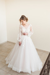 Beautiful bride wearing fashion wedding dress with feathers with luxury delight make-up and hairstyle, studio indoor photo shoot