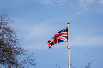 Union Jack flag against blue sky with clouds