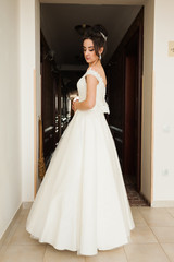 Fototapeta premium Beauty portrait of bride wearing fashion wedding dress with feathers with luxury delight make-up and hairstyle, studio indoor photo.
