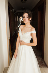 Fototapeta premium Beauty portrait of bride wearing fashion wedding dress with feathers with luxury delight make-up and hairstyle, studio indoor photo.