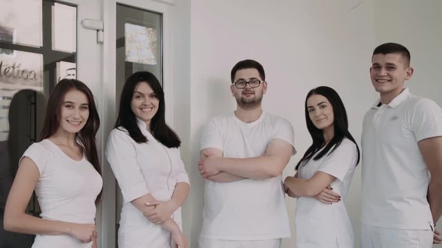 Portrait of happy, confident dentists look at camera with crossed hands
